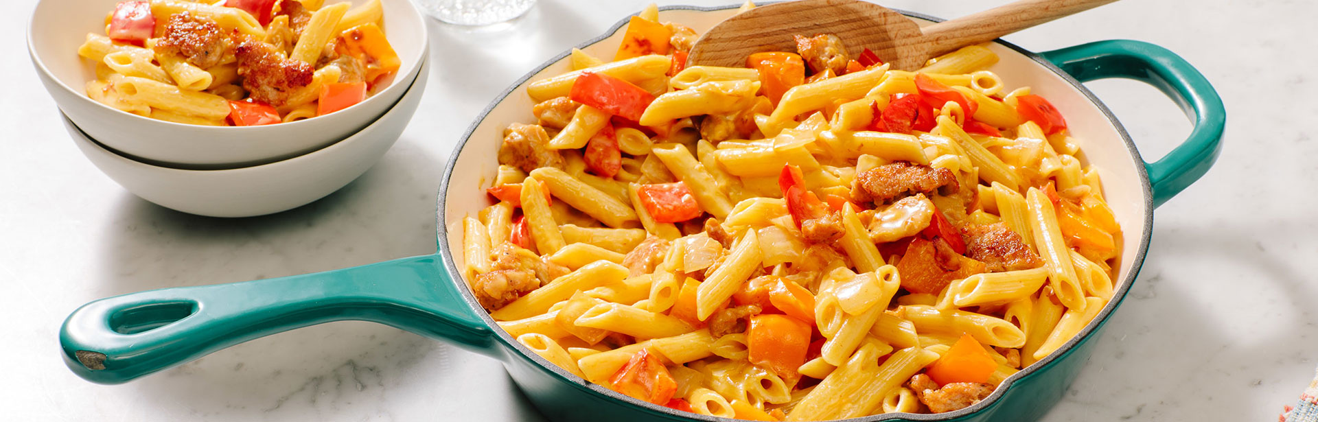 An image of prepared Skillet Sausage & Pepper Mac & Cheese made with pork sausage, Swanson® Unsalted Chicken Broth, Campbell's® Condensed Cheddar Cheese Soup, penne pasta, pepper and onion blend and Cheddar cheese.